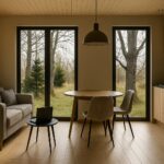 Moderne, offene Küche mit hochwertiger Holzverkleidung im Modulhaus ATHENA. Gemütlicher Essbereich mit stilvollen Möbeln und großen Panoramafenster.